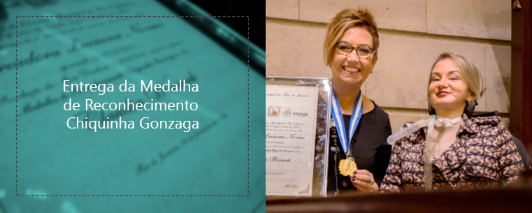 DESCRIÇÃO DA IMAGEM: Duas imagens, lado a lado. A primeira, na esquerda, está desfocada, com um título por cima dizendo “Entrega da Medalha de Reconhecimento Chiquinha Gonzaga”. A segunda, na direita, mostra duas mulheres, lado a lado, sorrindo. A mulher na esquerda segura um certificado em uma mão, e uma medalha, que está ao redor do seu pescoço, na outra. 